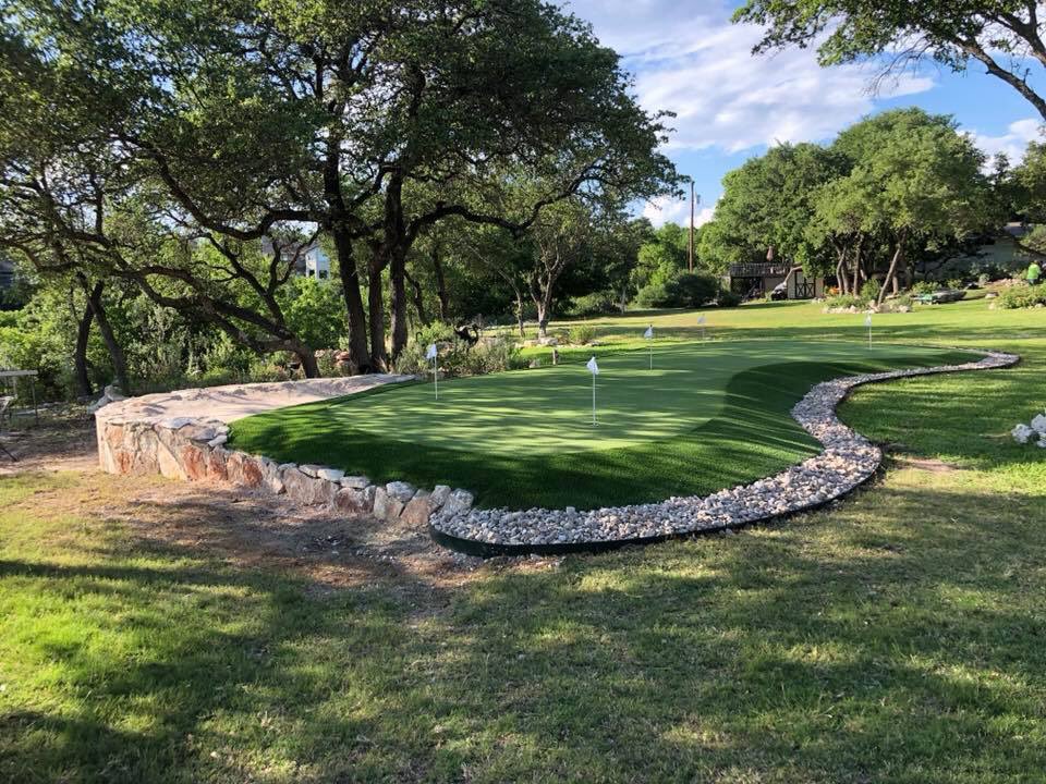 custom backyard putting green with rock edging and large gravel border
