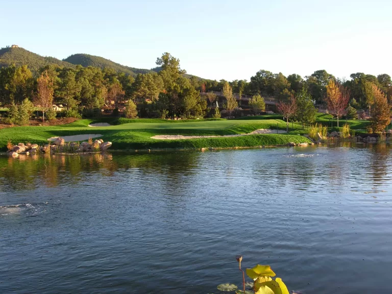 Signature putting green with artificial turf, sculpted bunkers, and lakeside landscaping by Celebrity Greens®